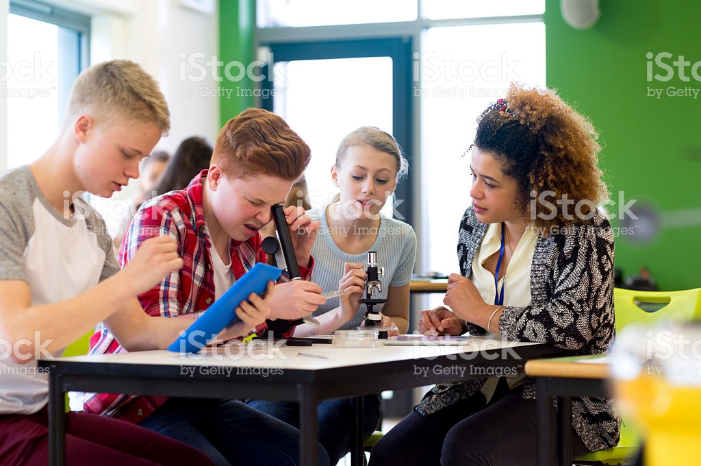 teacher and students looking in microscopes