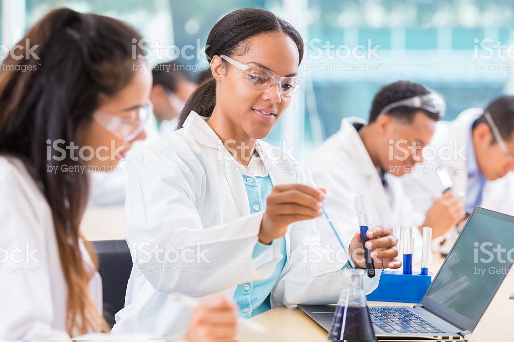 Woman with white coat, goggles and test tubes