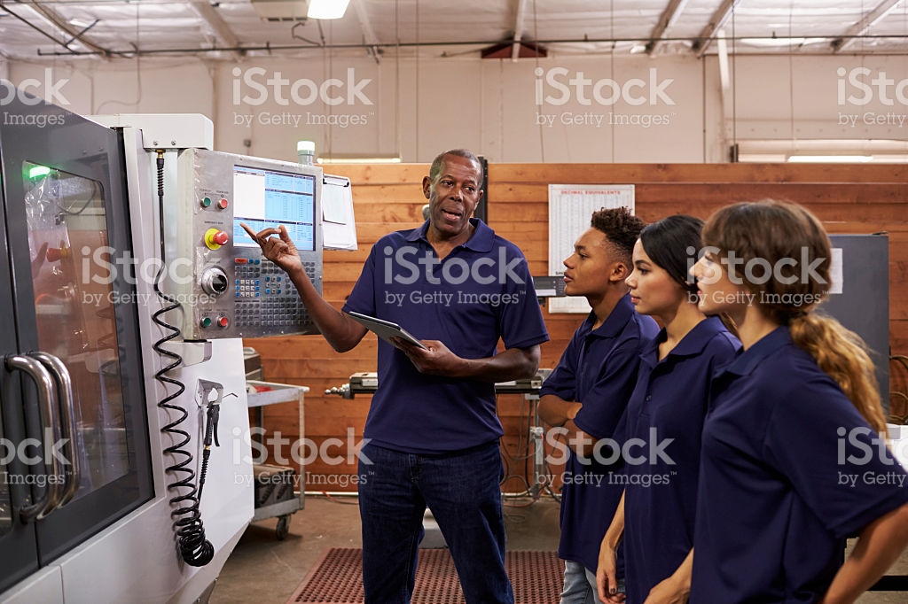 Man explaining machine to interns