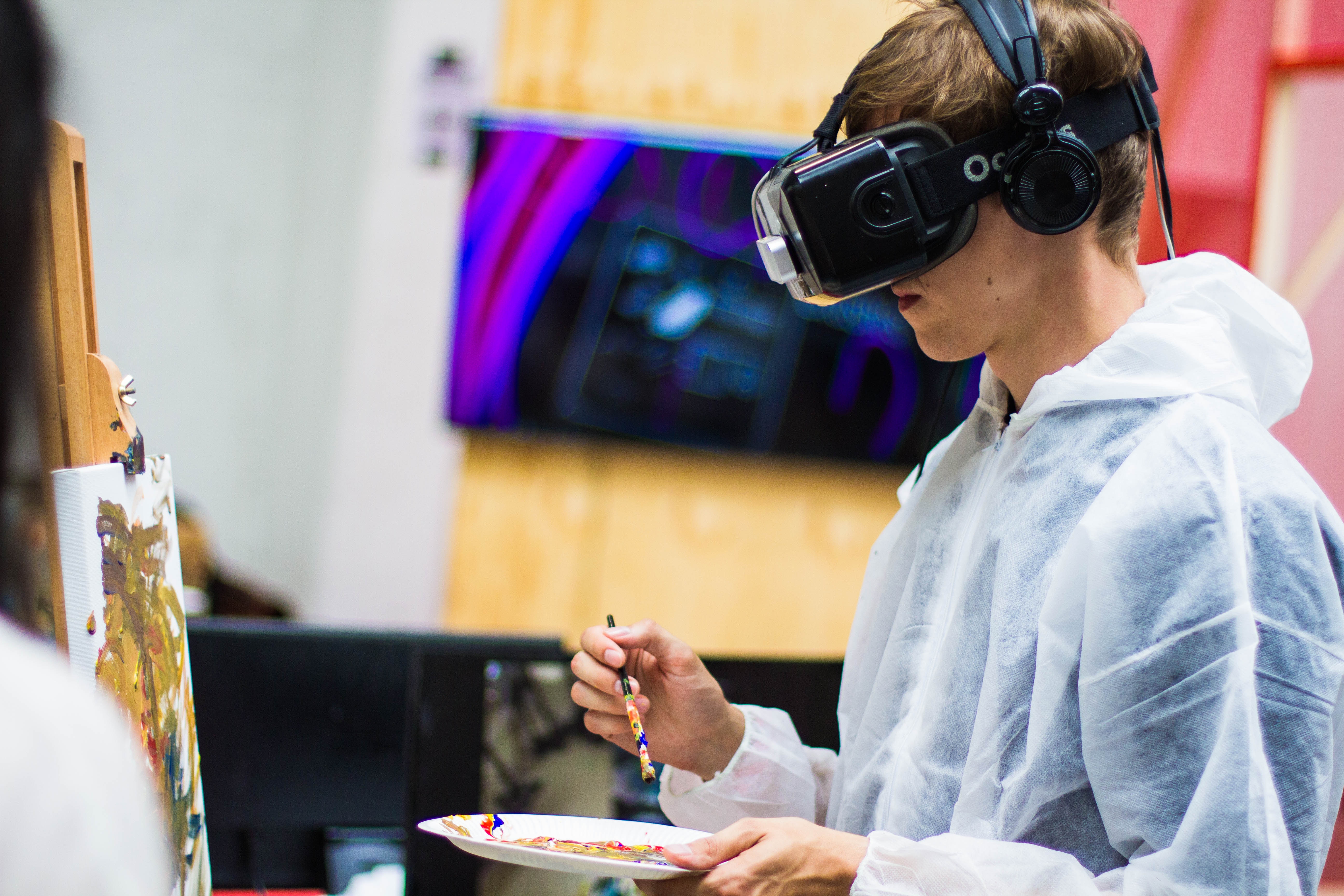 Teenage boy painting while wearing VR glasses